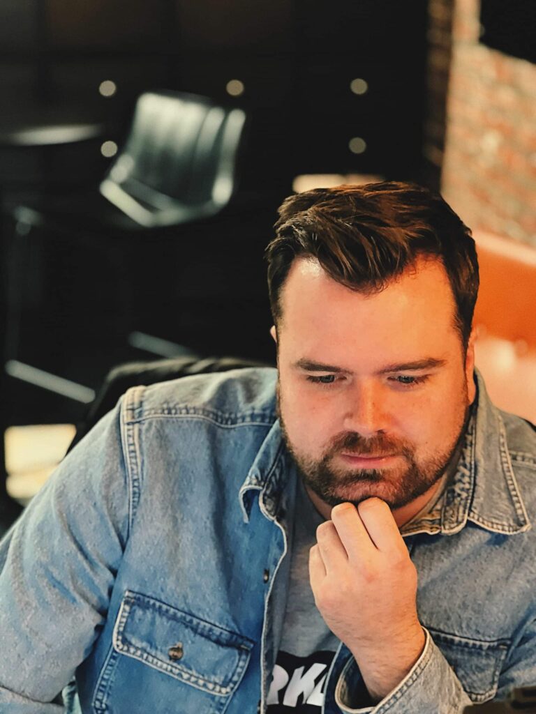 Candid photo of Zach Karl working at his desk with his hand on his chin